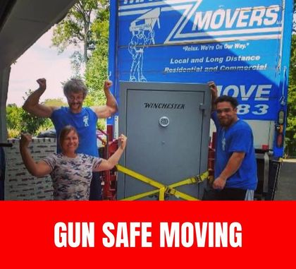 Two professional movers using lifting straps and a dolly to transport a large gun safe safely down a hallway.