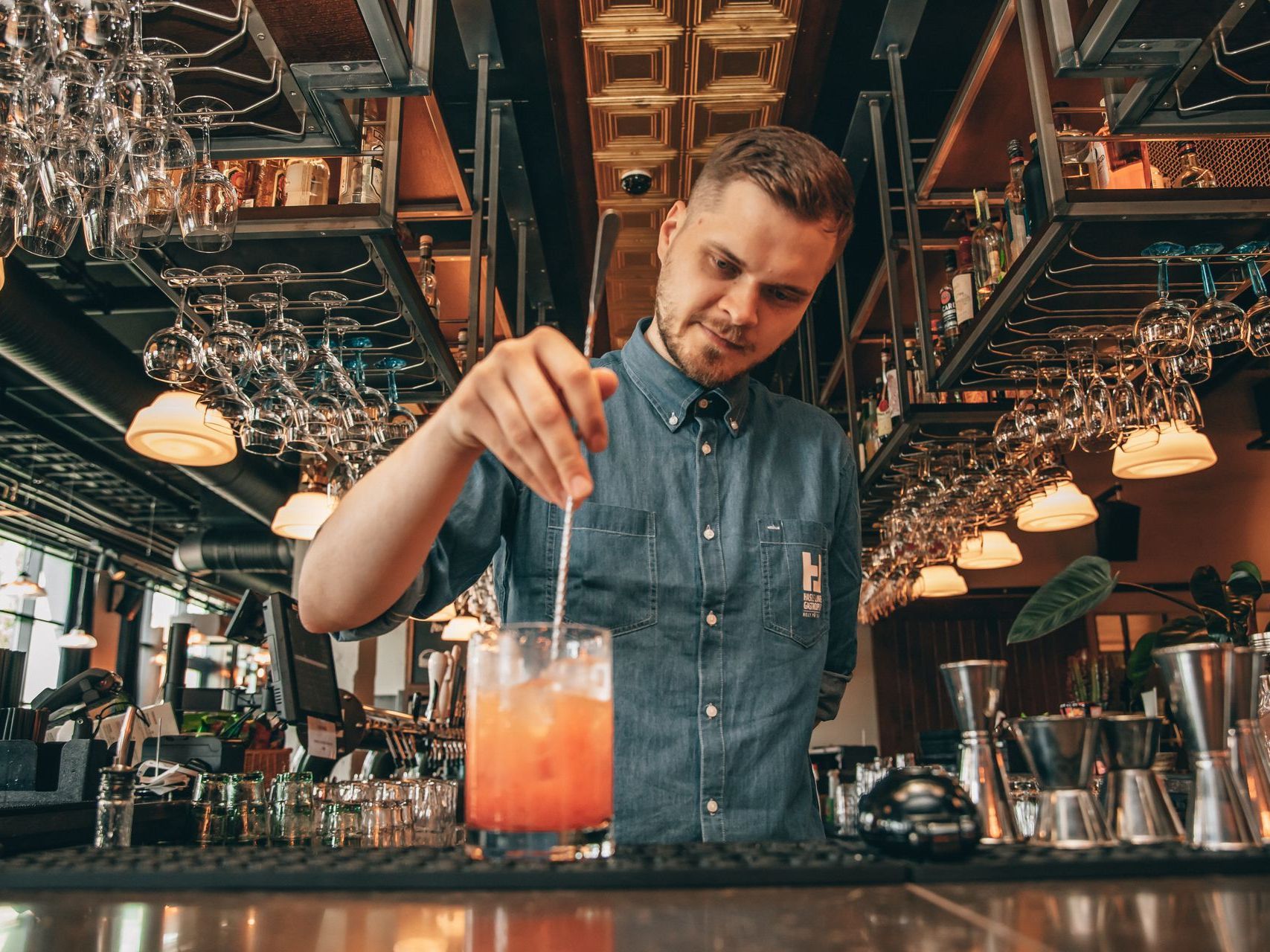 En bartender skjenker en drink i et glass på en bar.