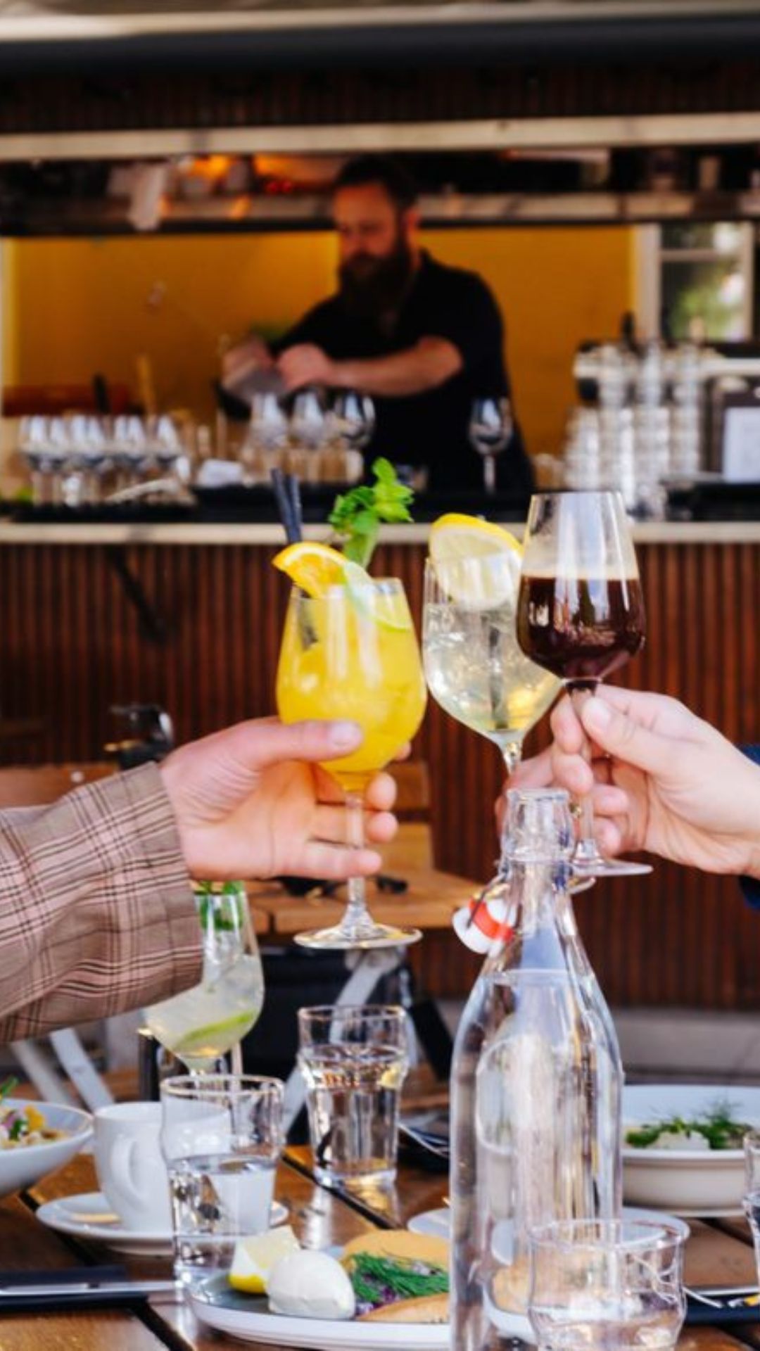 En gruppe mennesker skåler med drinker på en restaurant.