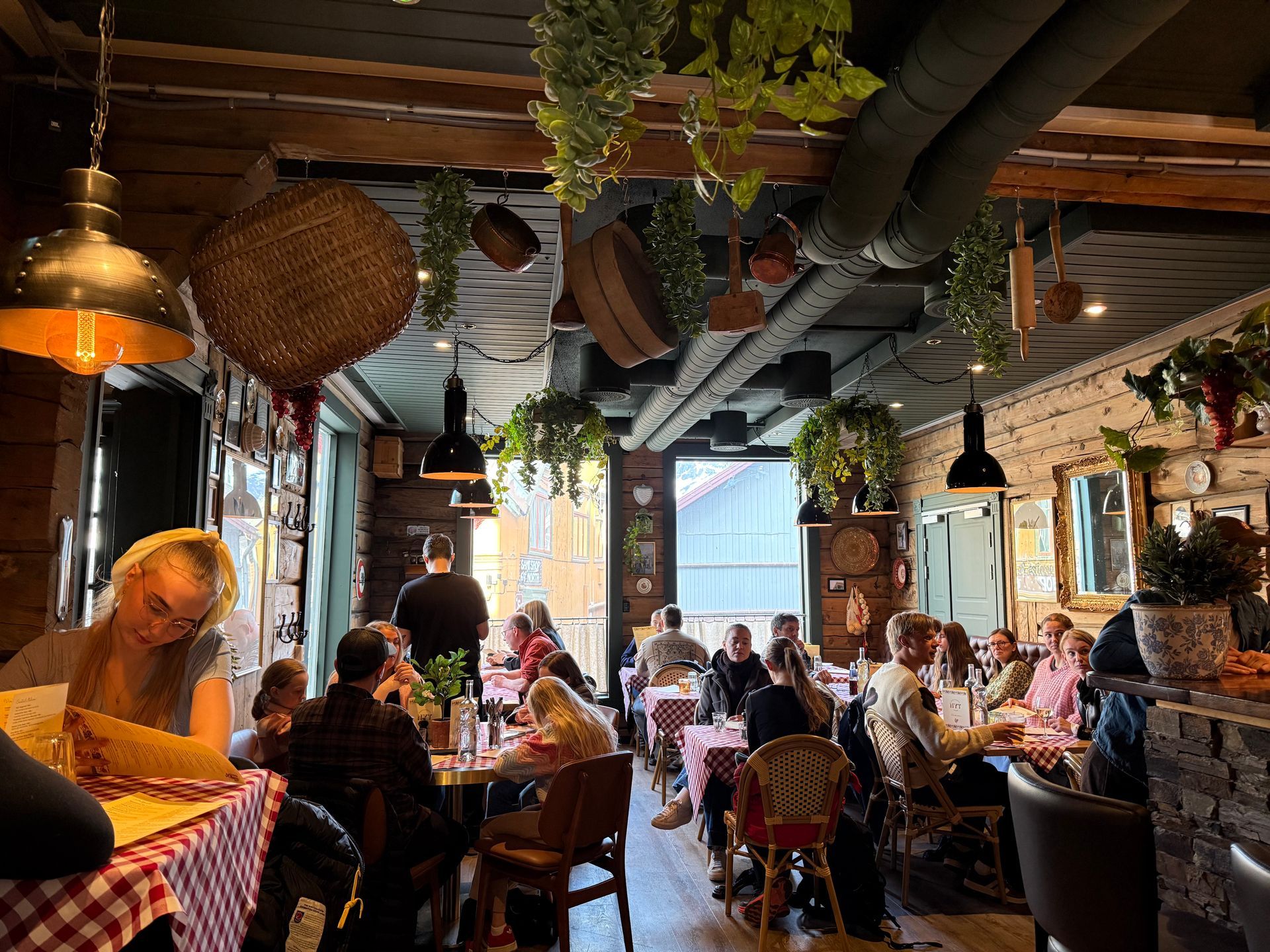 Travel, varmt opplyst restaurant med folk sittende ved bord under hengende planter og flettede kurver