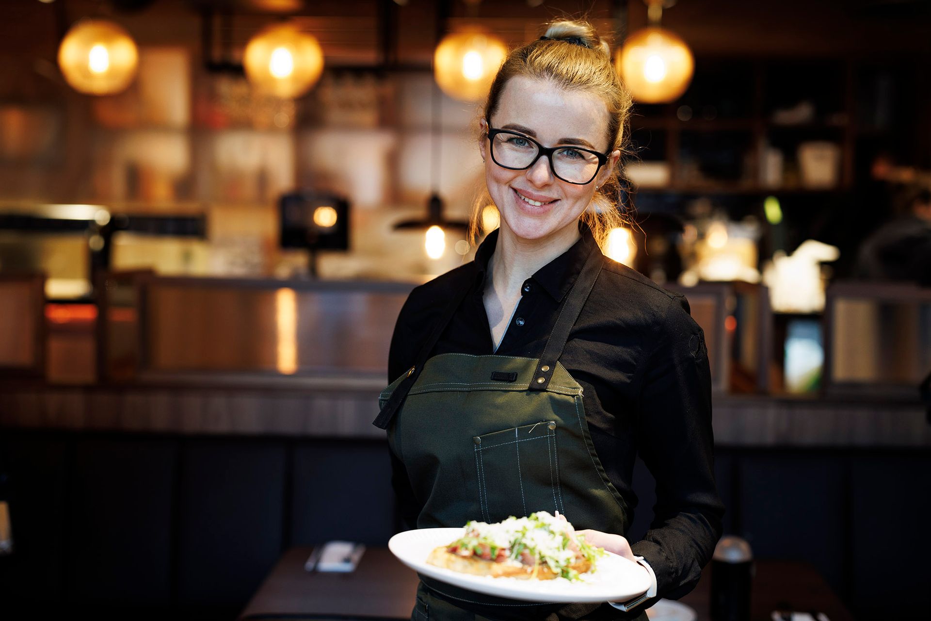En servitør holder en tallerken med mat på en restaurant.