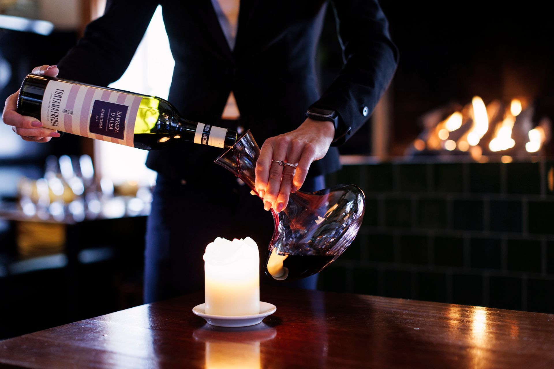 En person heller en flaske vin i en karaffel.