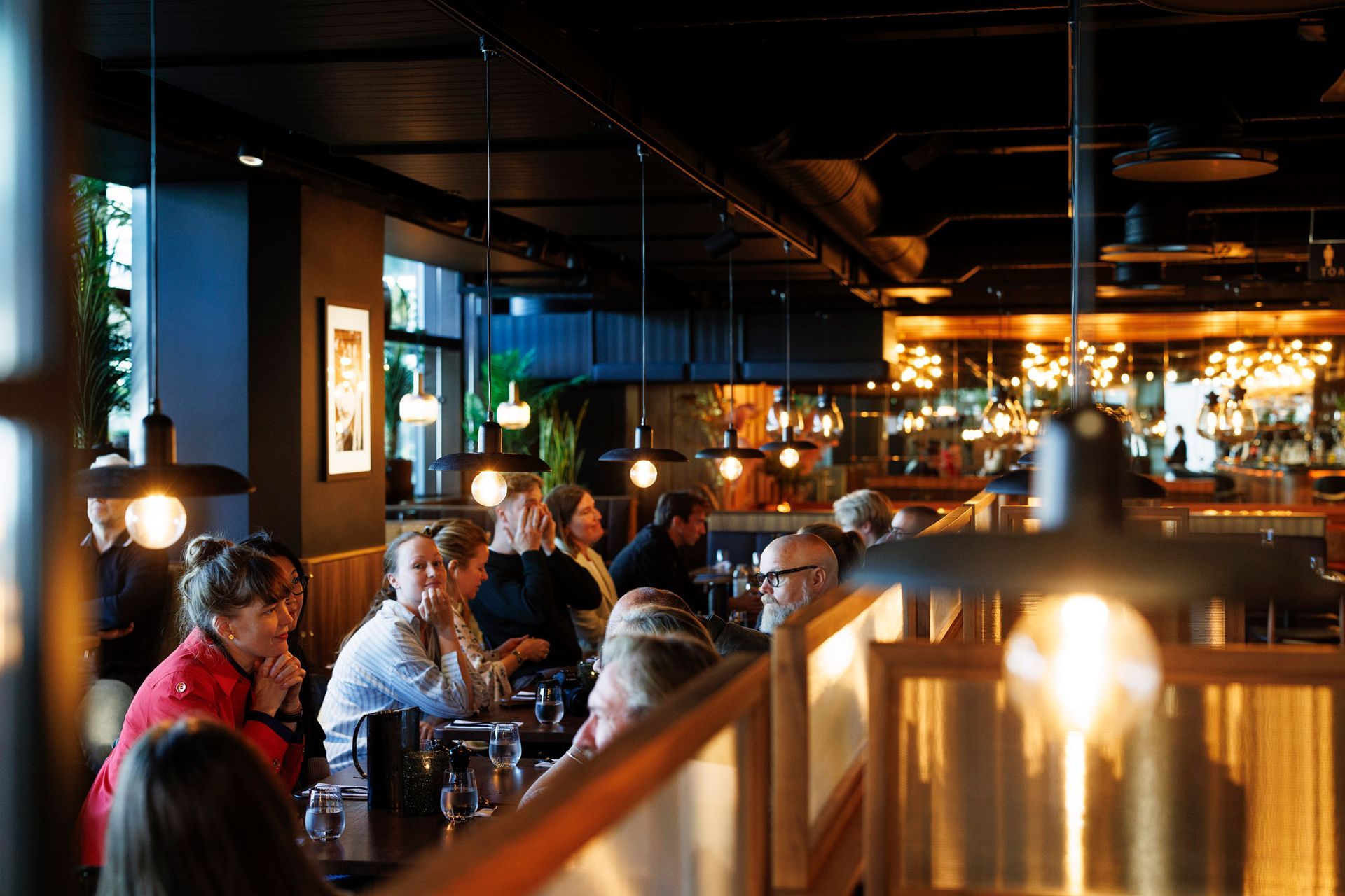 En gruppe mennesker sitter ved bordene på en restaurant.