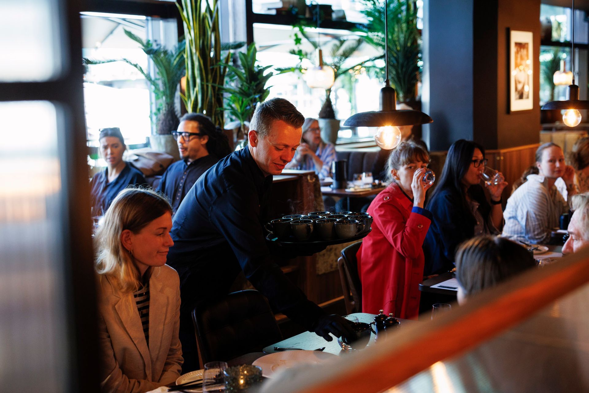 En gruppe mennesker sitter ved bordene på en restaurant.