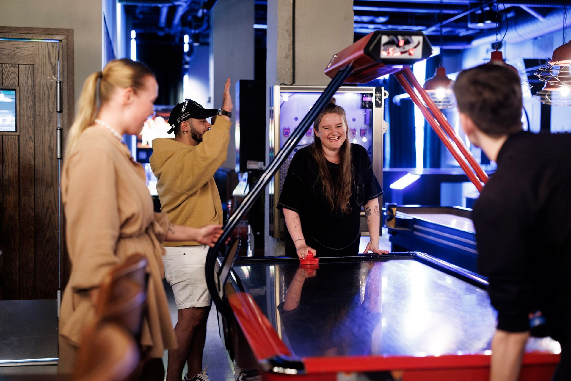 En gruppe mennesker spiller airhockey på et bord.