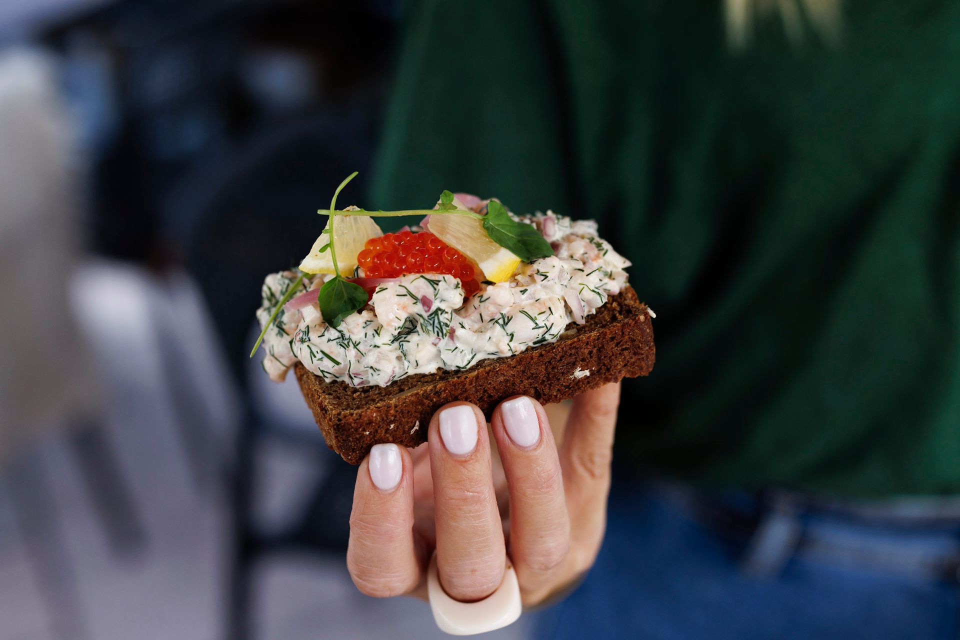 En kvinne holder et stykke brød med en salat på.