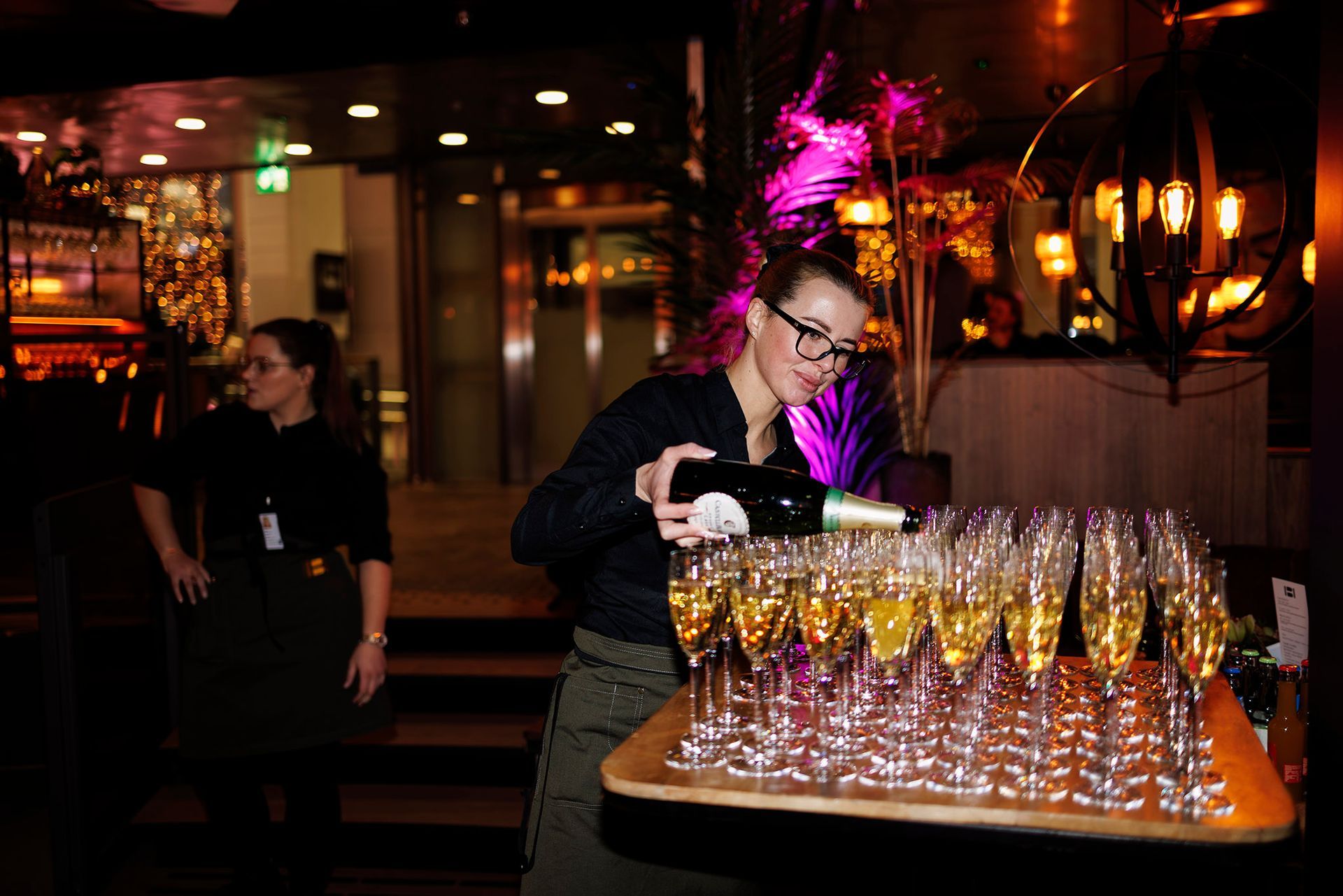 En kvinne skjenker champagne i glass på et bord