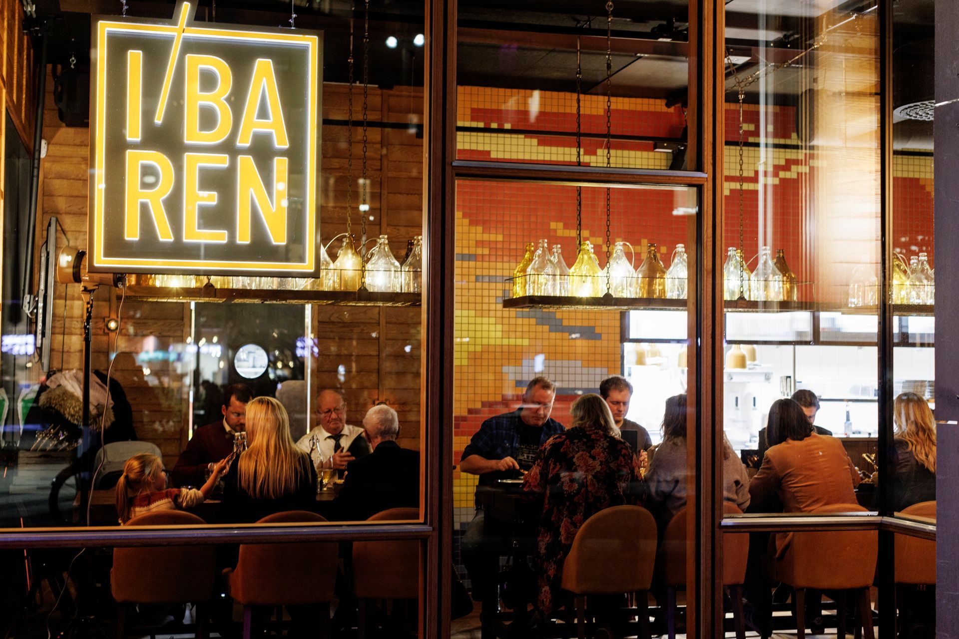 En gruppe mennesker sitter ved bordene på en restaurant.