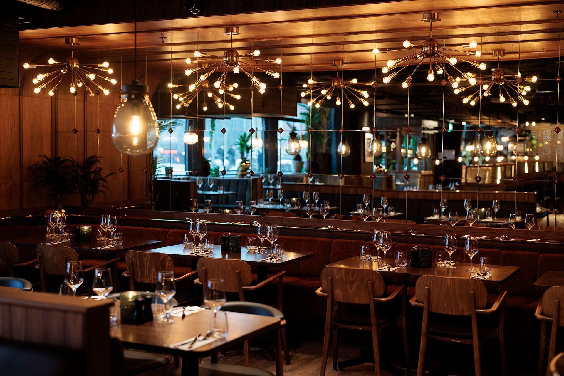En restaurant fylt med bord og stoler og massevis av lys.