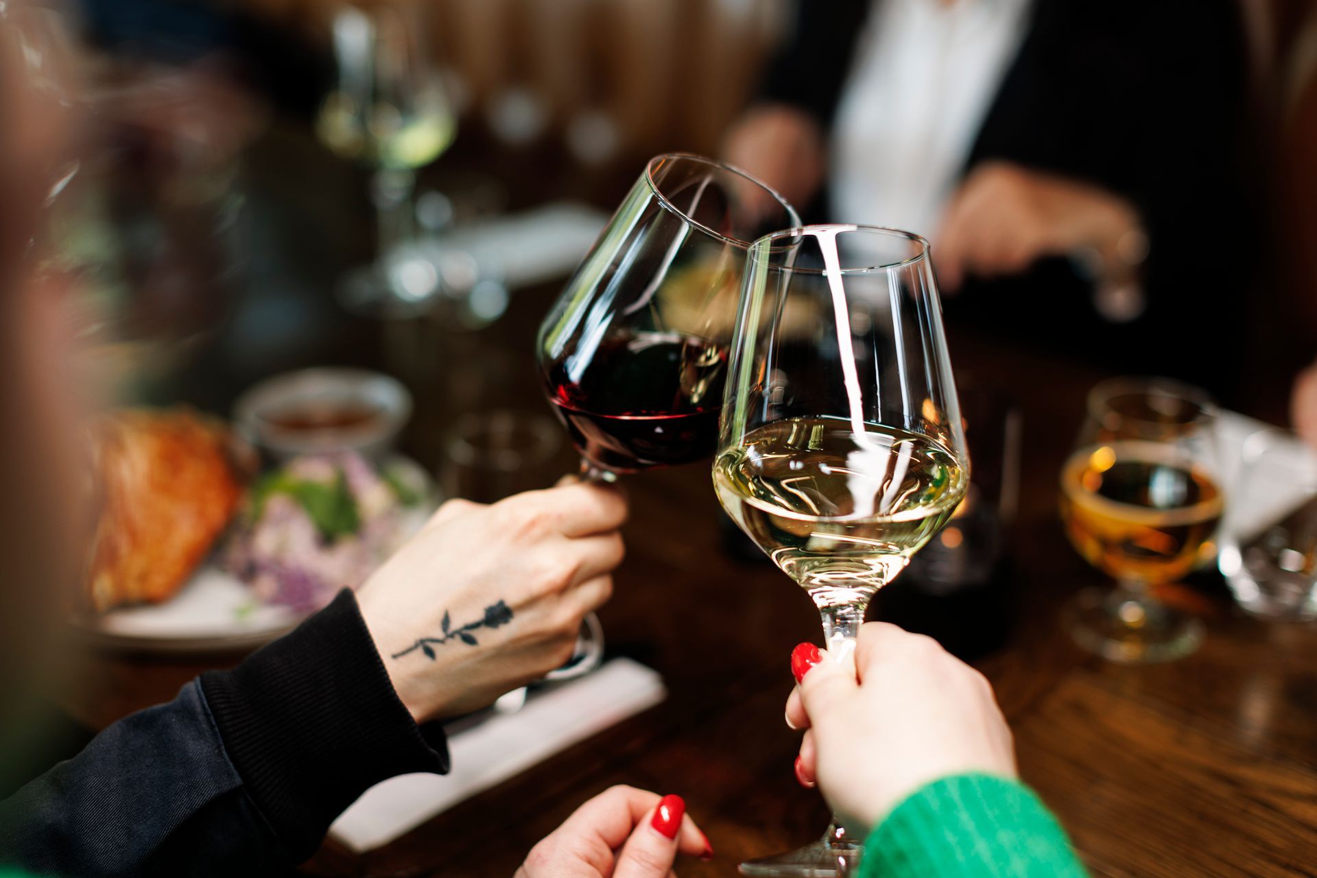 To personer skåler for vinglass, ett rødt og ett hvitt, ved et restaurantbord.