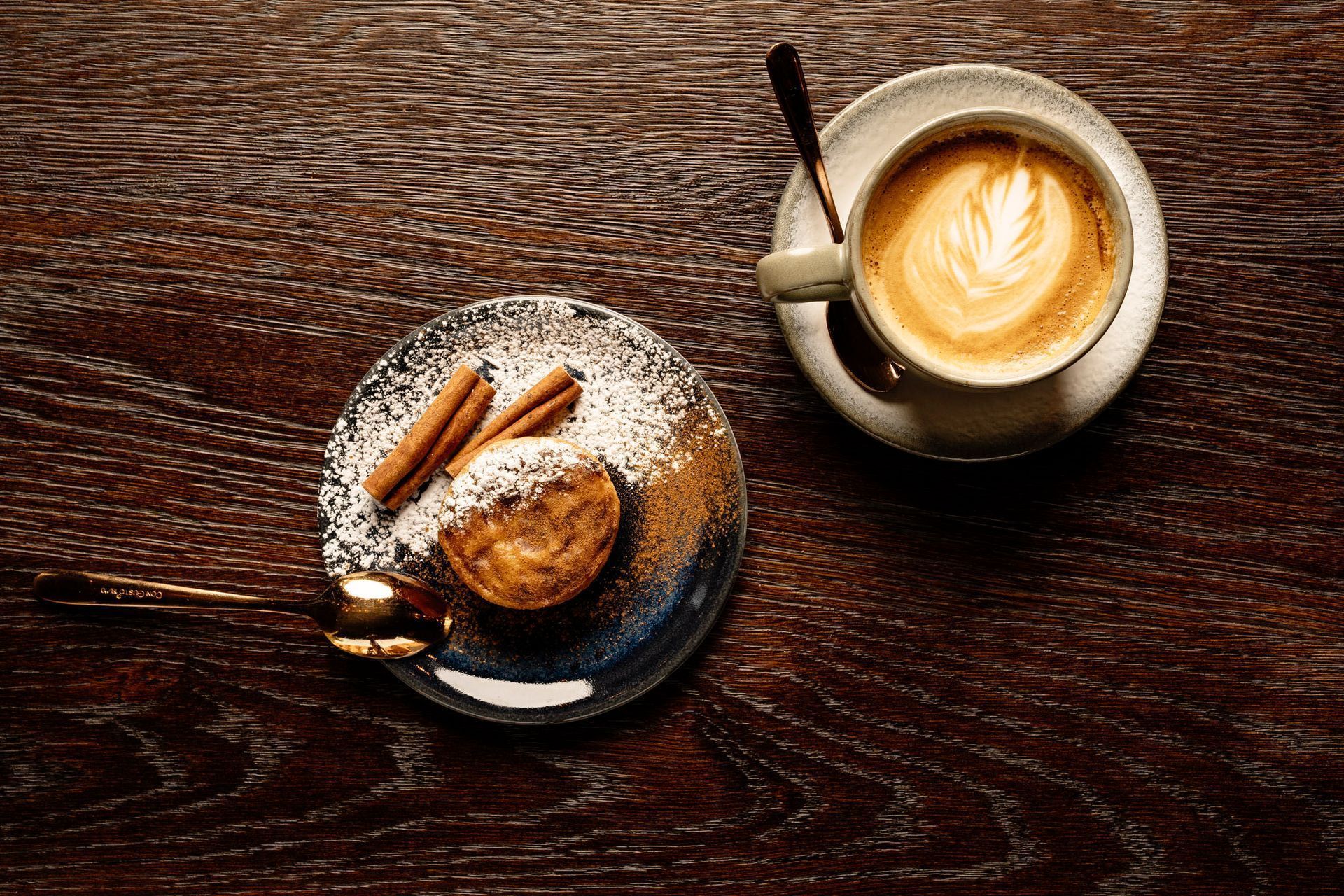 En kopp kaffe og en tallerken med dessert på et trebord.