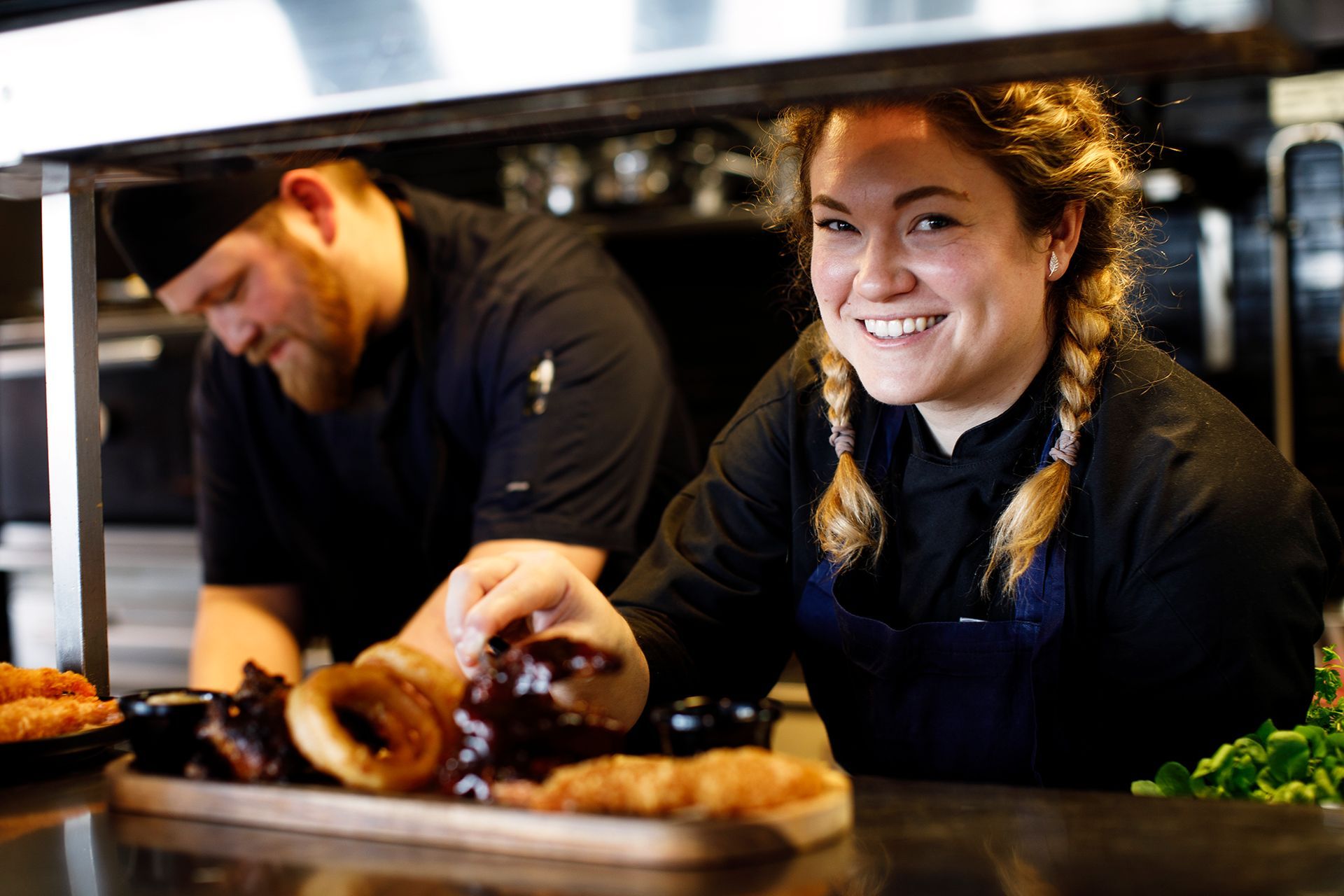 En mann og en kvinne står på et kjøkken og lager mat.