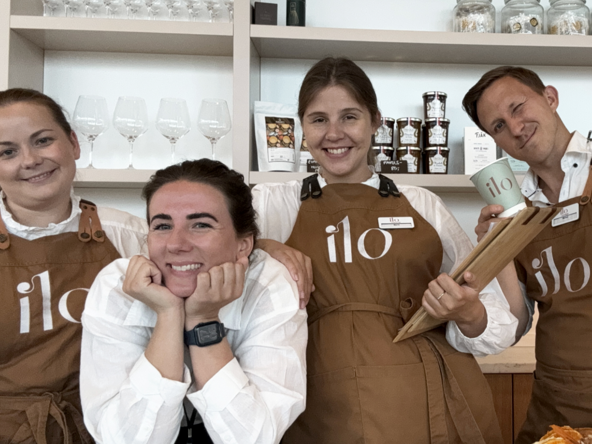 Fire personer med «ilo»-forklær smiler til kameraet i en butikk.