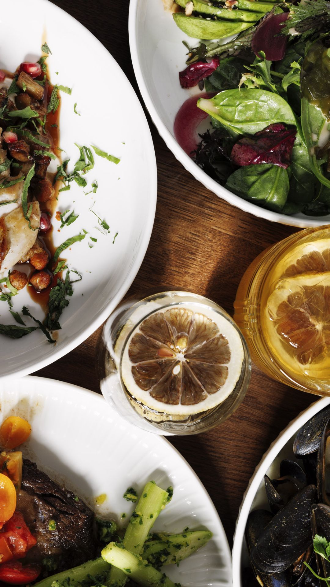 Et bord toppet med tallerkener med mat og et glass vin.