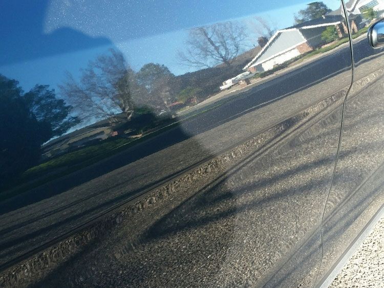 A close up of a car with a reflection of a house in the window