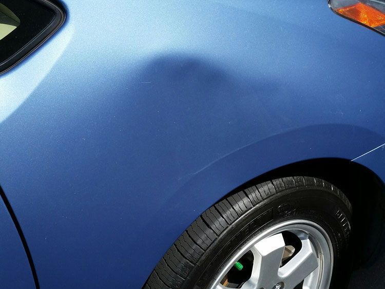 A close up of a blue car with a black tire