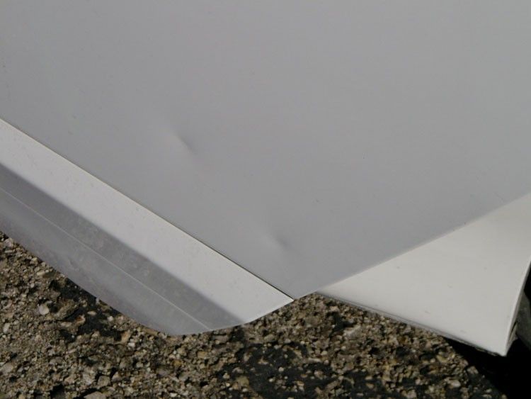 A close up of a white car door on a gravel road.