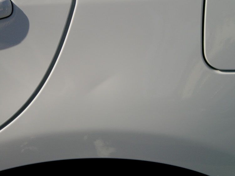 A close up of a white car with a fuel cap