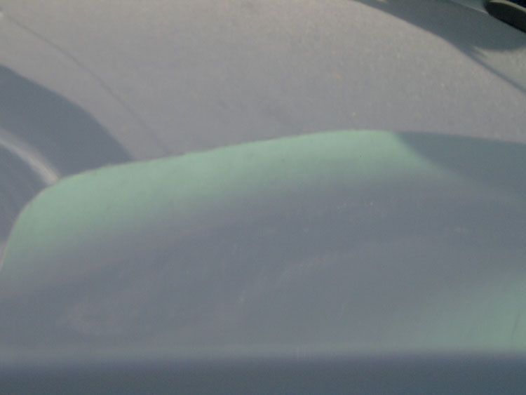 A close up of a car windshield with a green shadow on it.