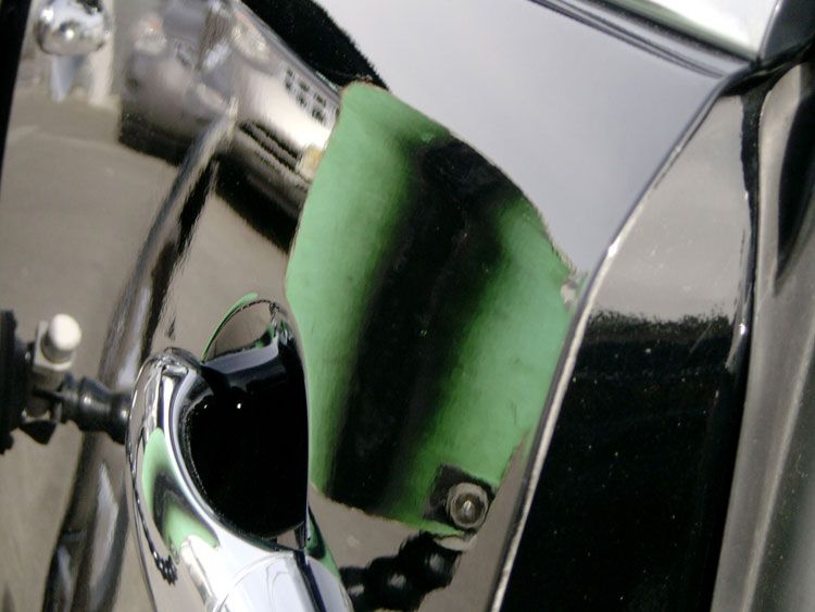 A black car with a green piece of tape on it