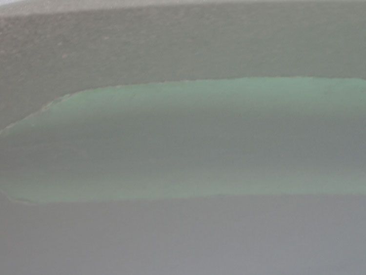 A close up of a bathtub filled with green water.