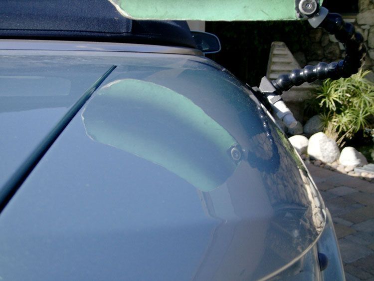 A close up of a car windshield with a green roof