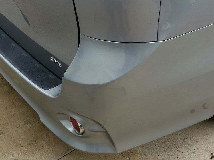 A silver car is parked on the side of the road
