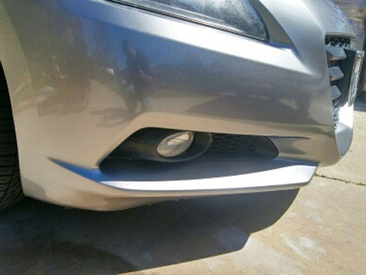 A silver car is parked on the side of the road