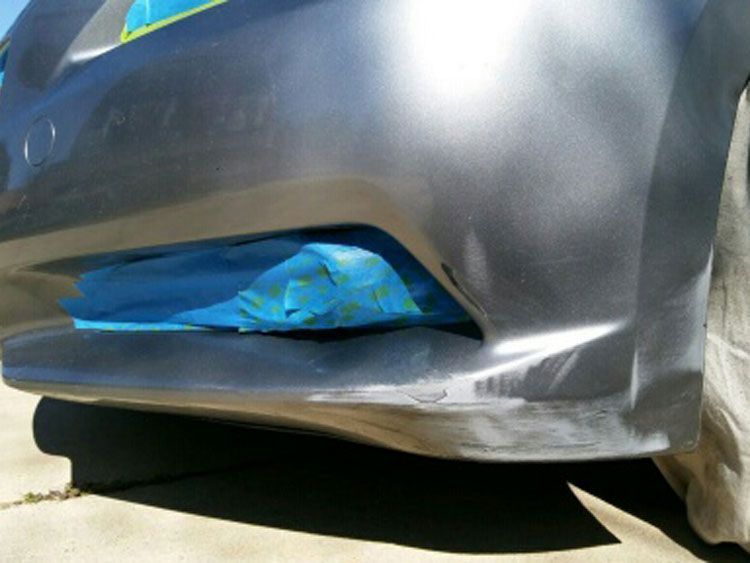 A close up of a car bumper with blue tape on it