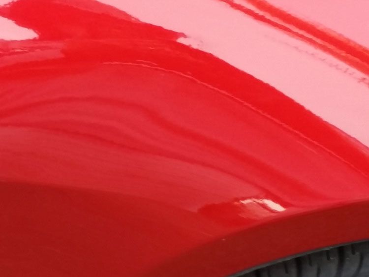 A close up of a red car 's fender and tire.