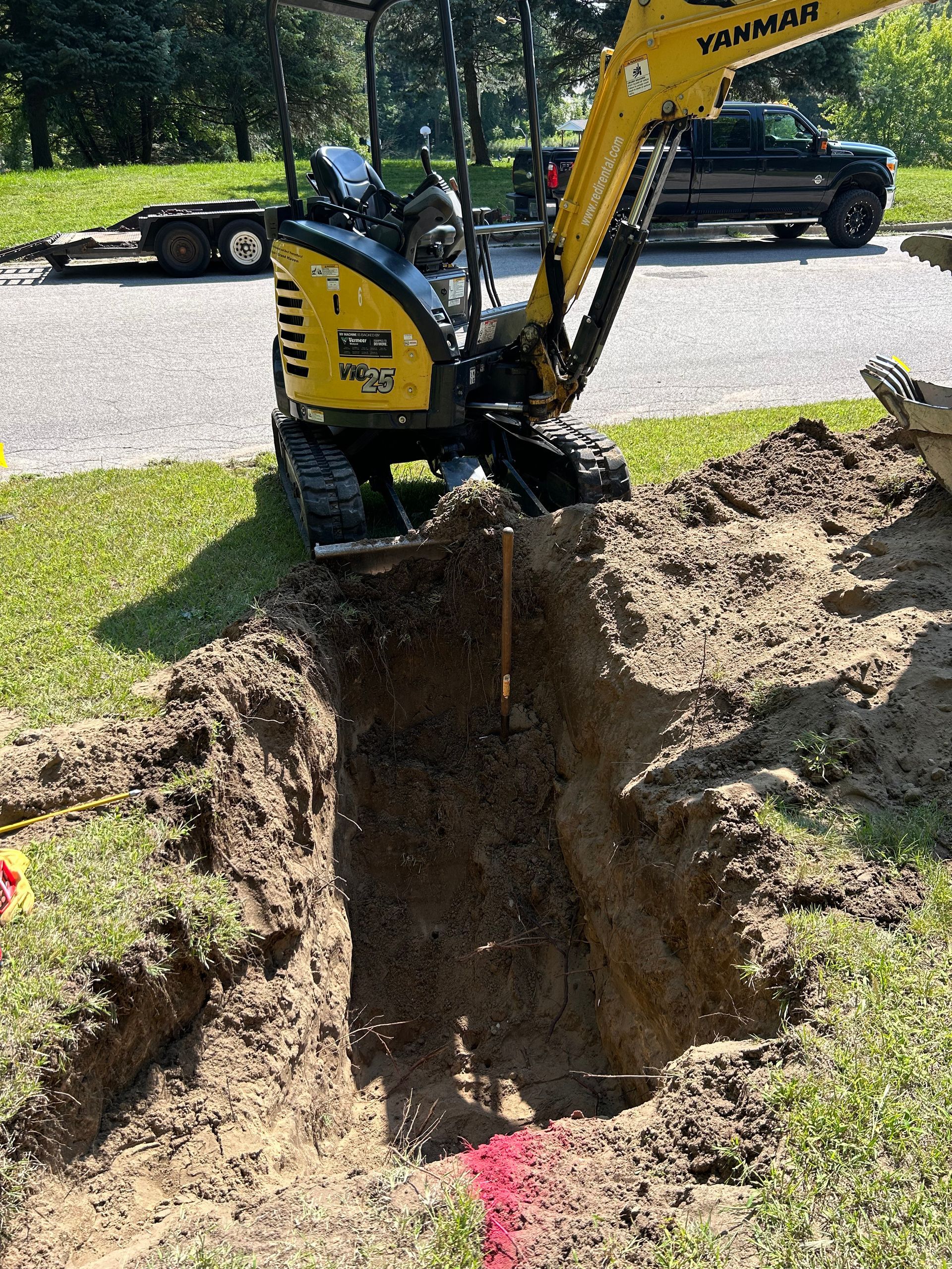 A yellow excavator is digging a hole in the ground.