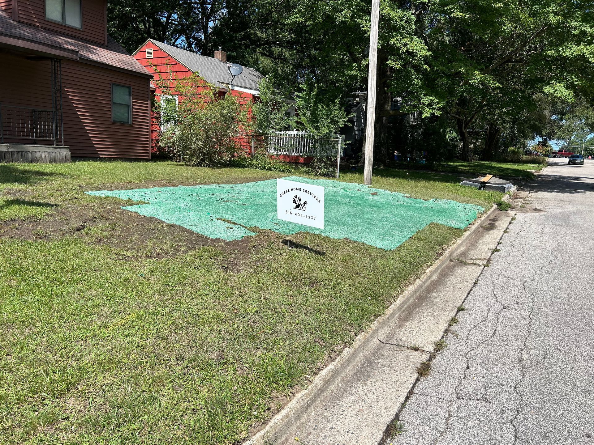 A green tarp is covering a grassy area in front of a house.