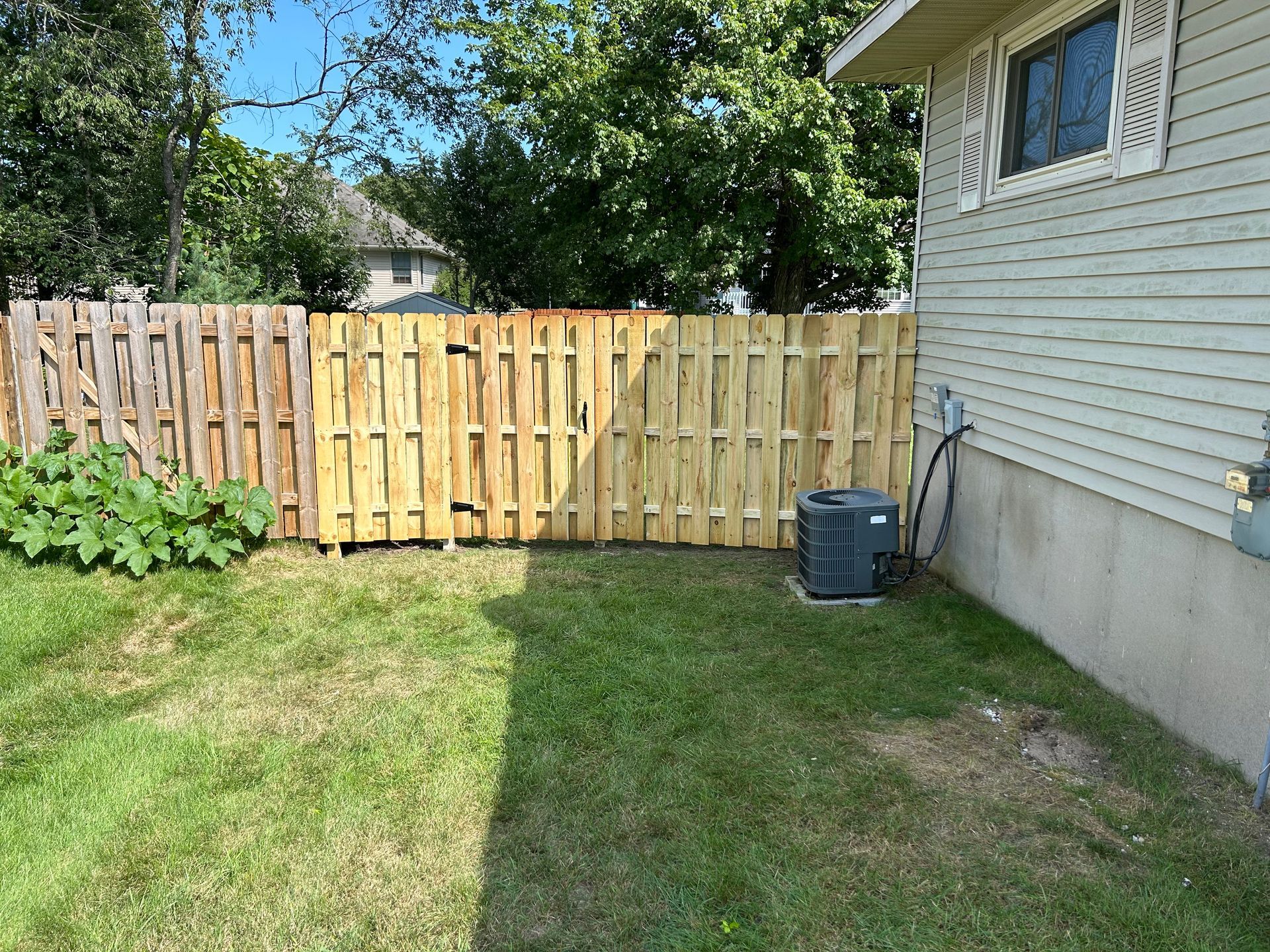 A wooden fence is in the backyard of a house.