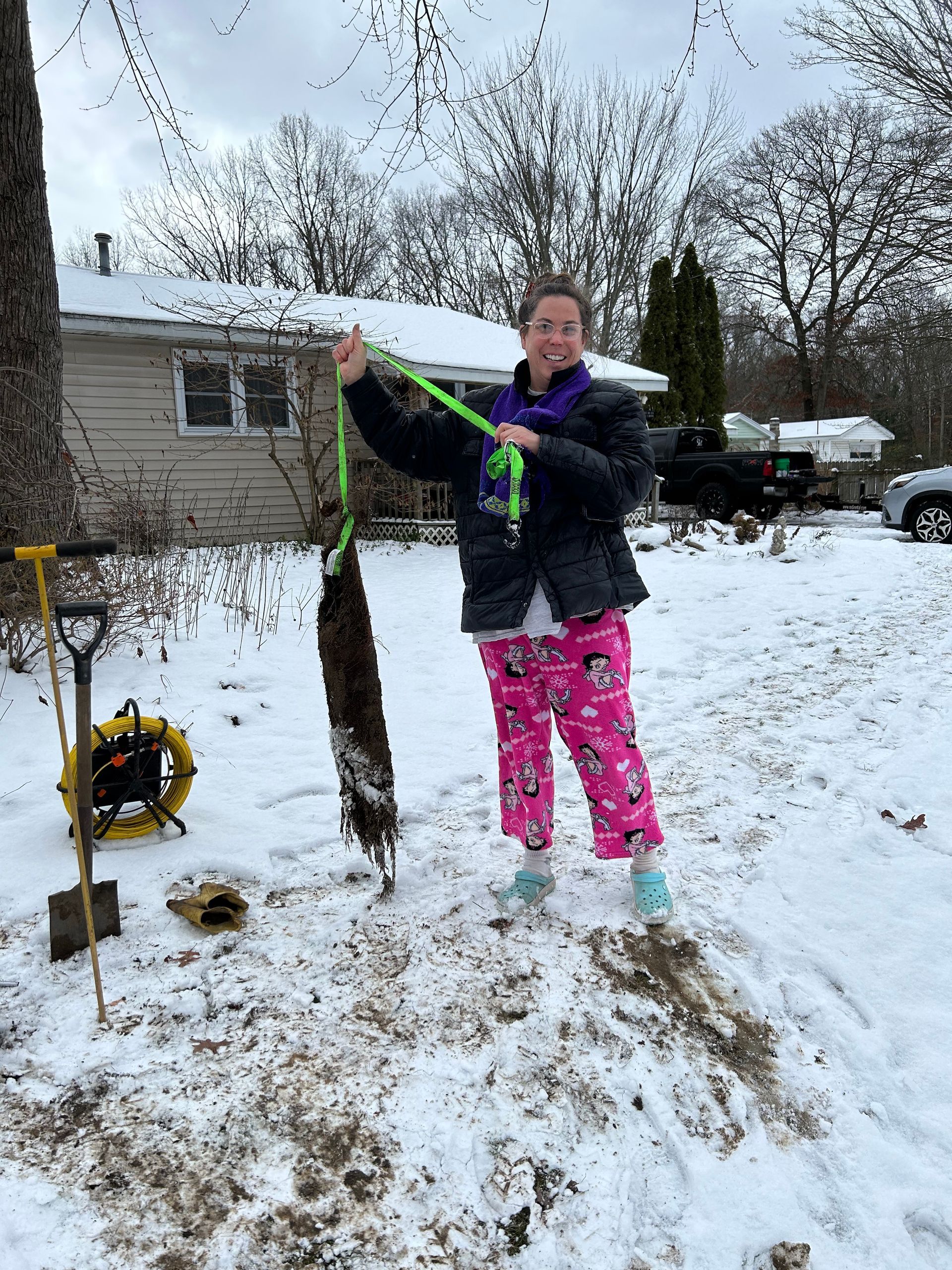 A woman is standing in the snow holding a green rope.
