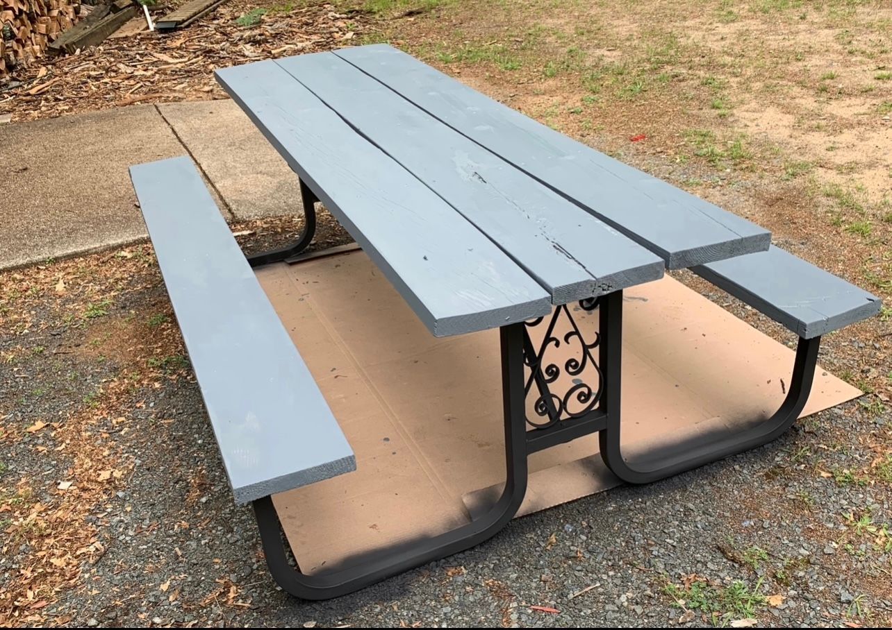 A gray picnic table is sitting on the ground