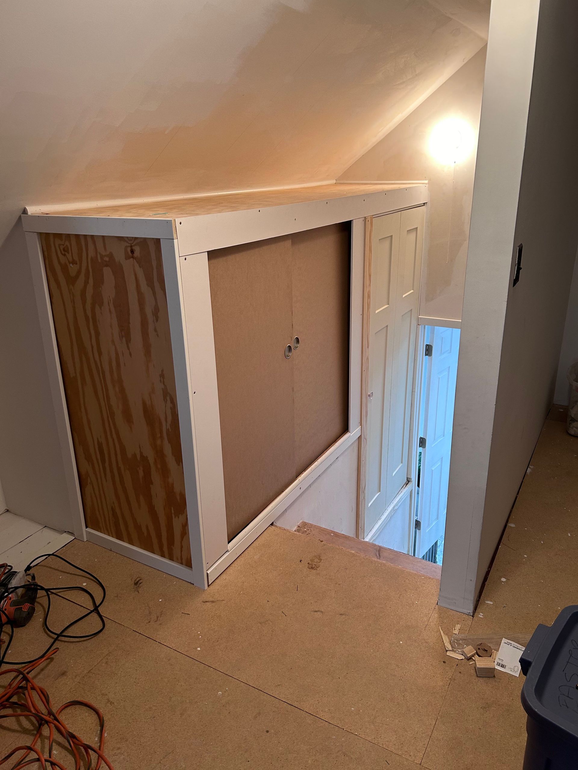 A room with a staircase leading up to a closet.