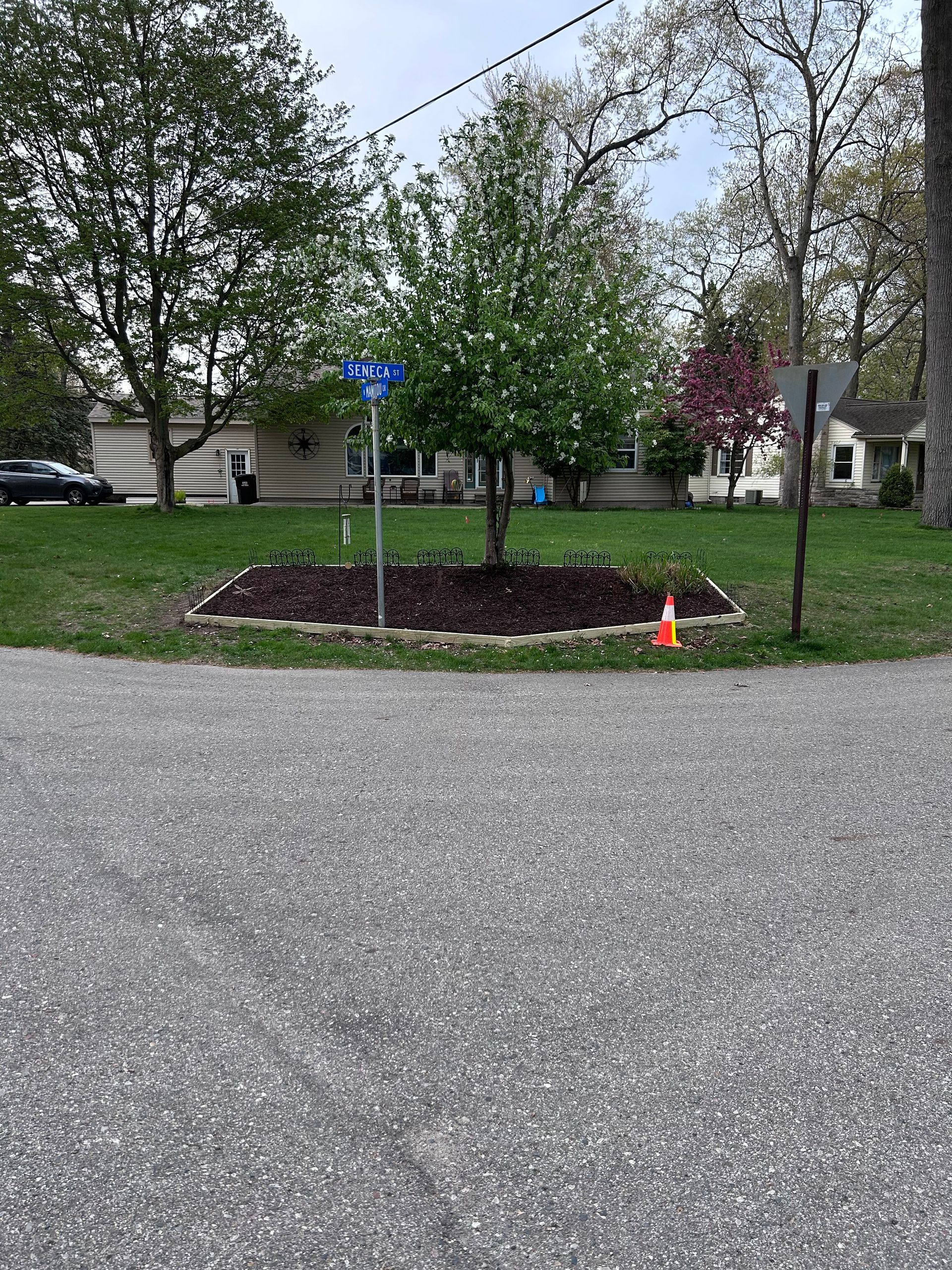 A gravel driveway with a flower bed in the middle of it.