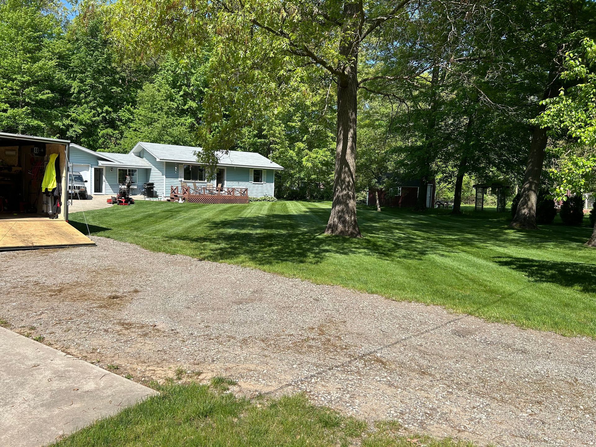 A driveway leading to a house surrounded by trees and grass.