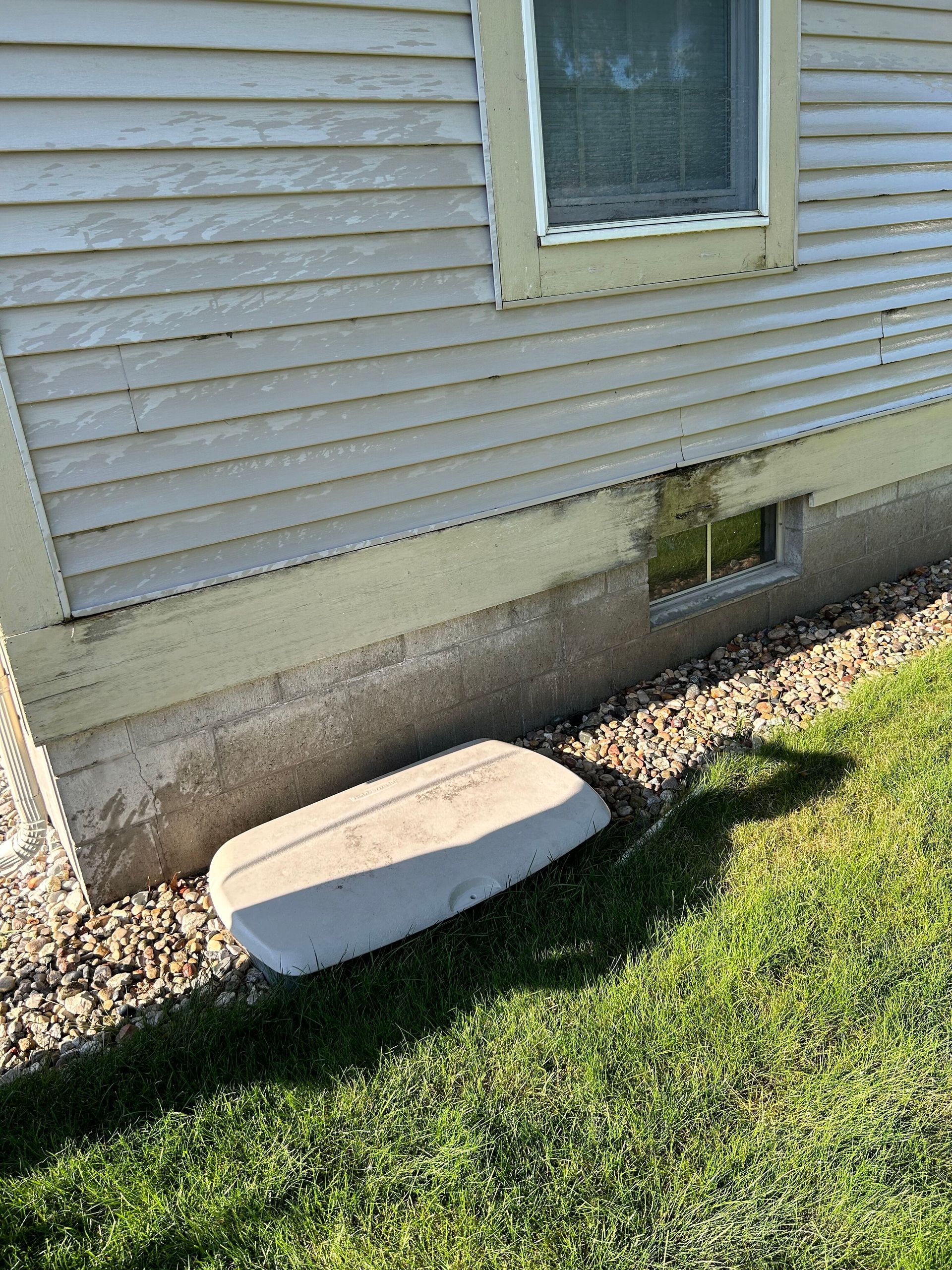 A white house with a window and a concrete block in front of it.