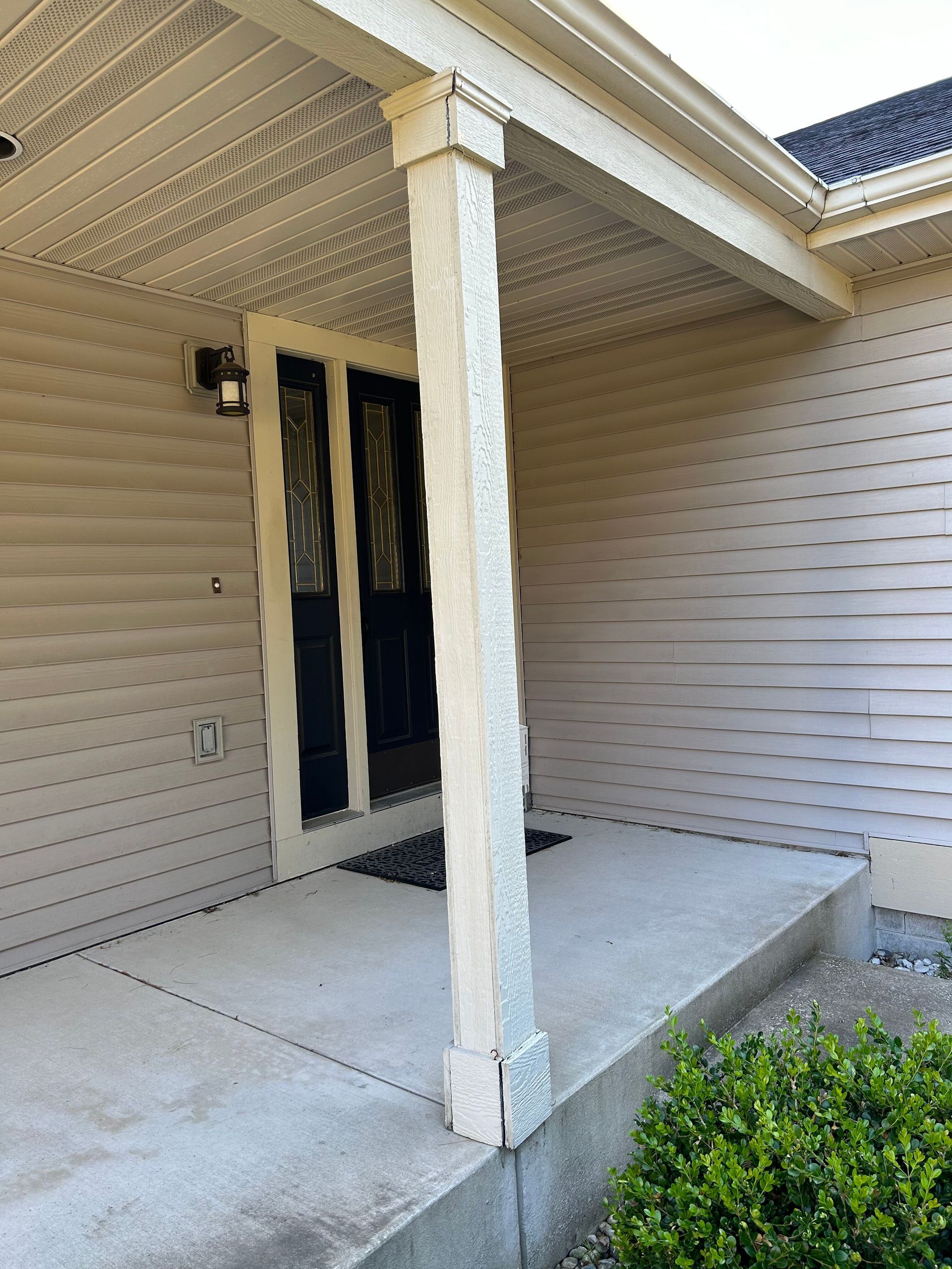 A white house with a porch and a black door.