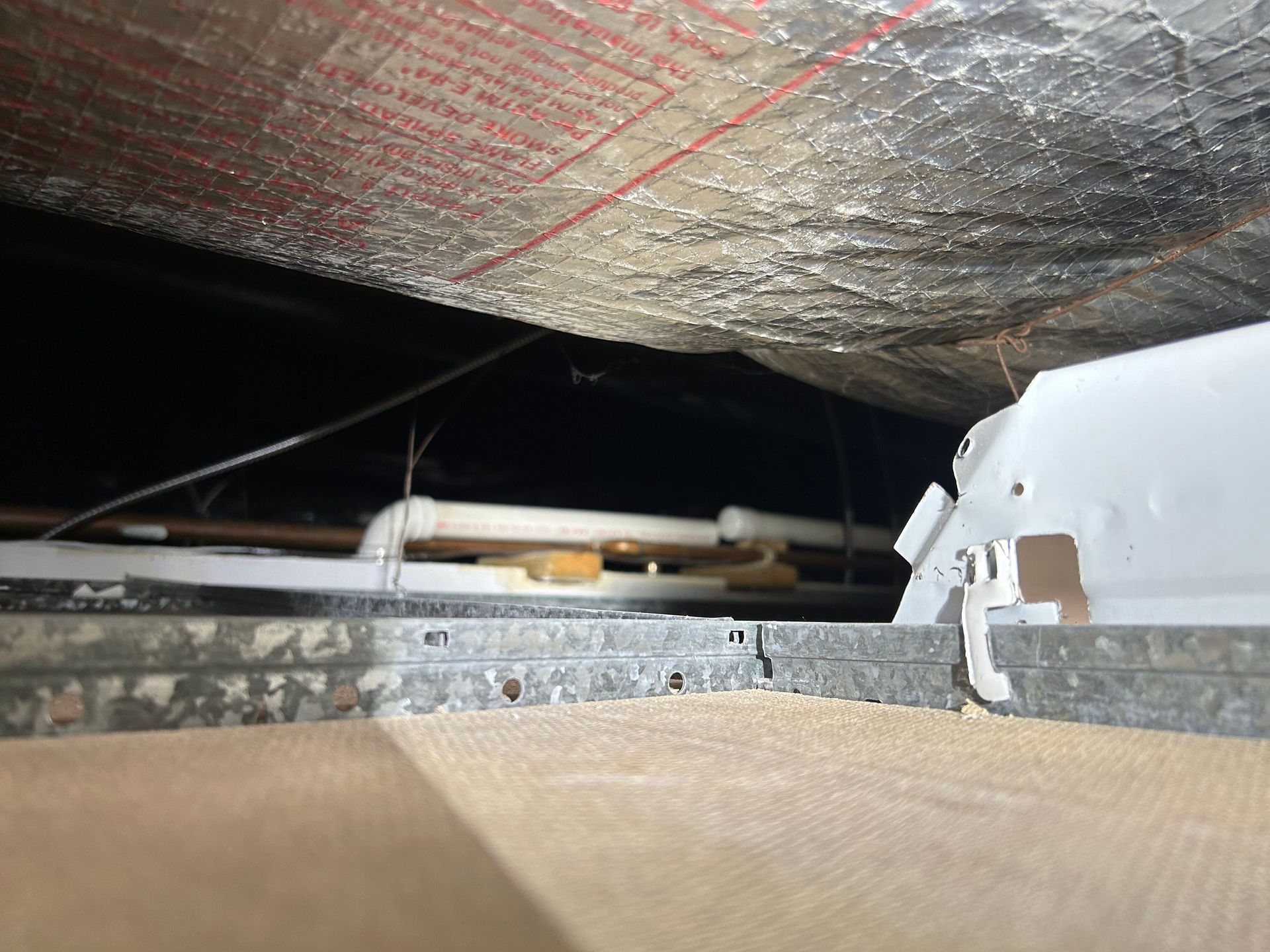 A ceiling with a lot of pipes hanging from it.