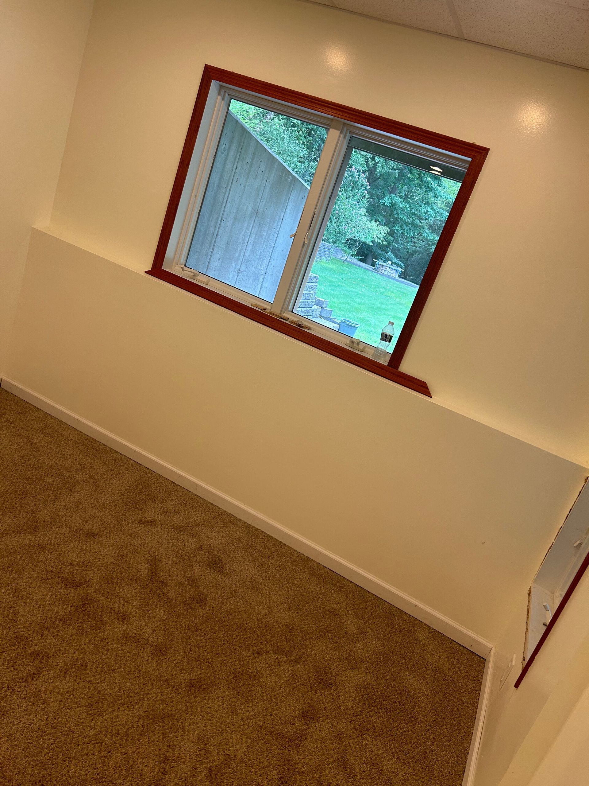 A room with a window and a carpeted floor.
