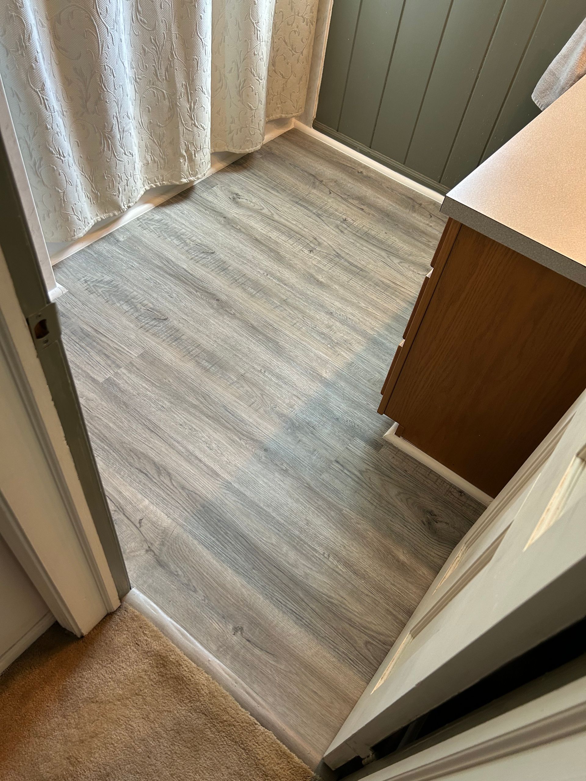 A bathroom with a wooden floor and a shower curtain.