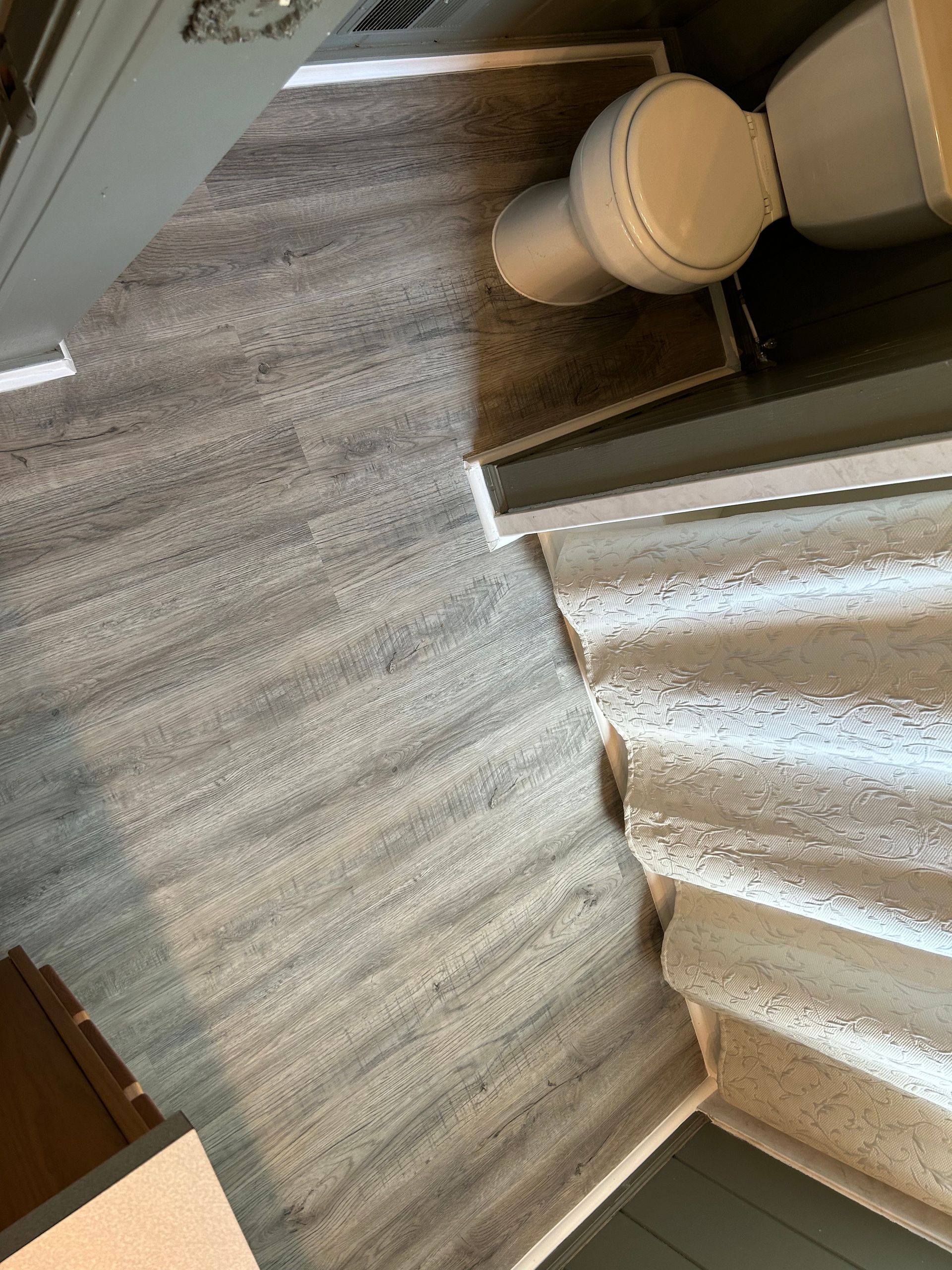 A bathroom with a toilet , shower curtain and stairs.