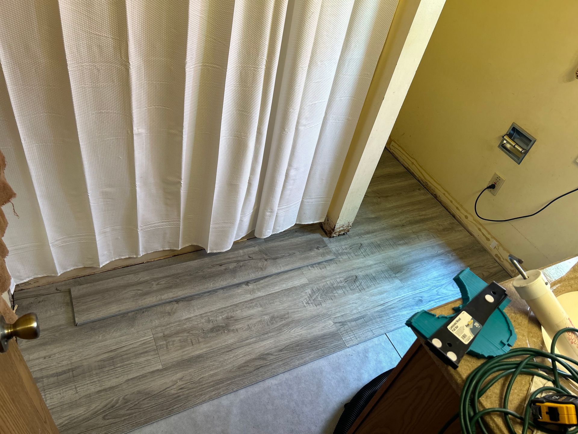A bathroom with a shower curtain and a wooden floor.