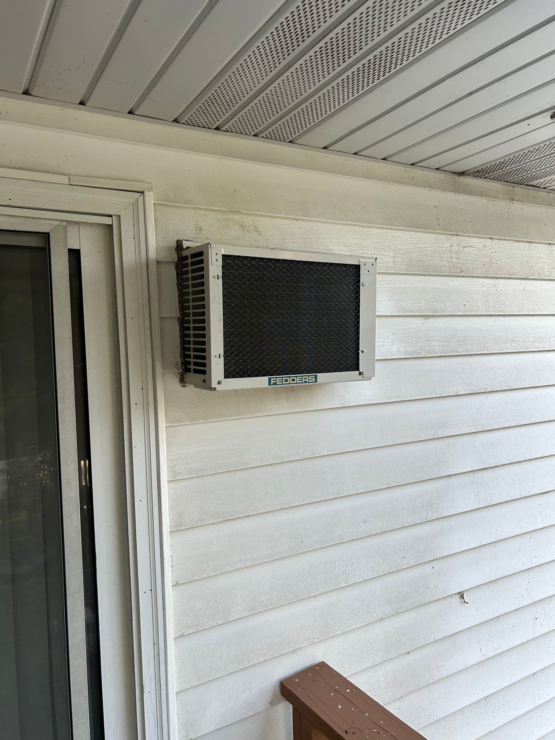 An air conditioner is mounted on the side of a house.