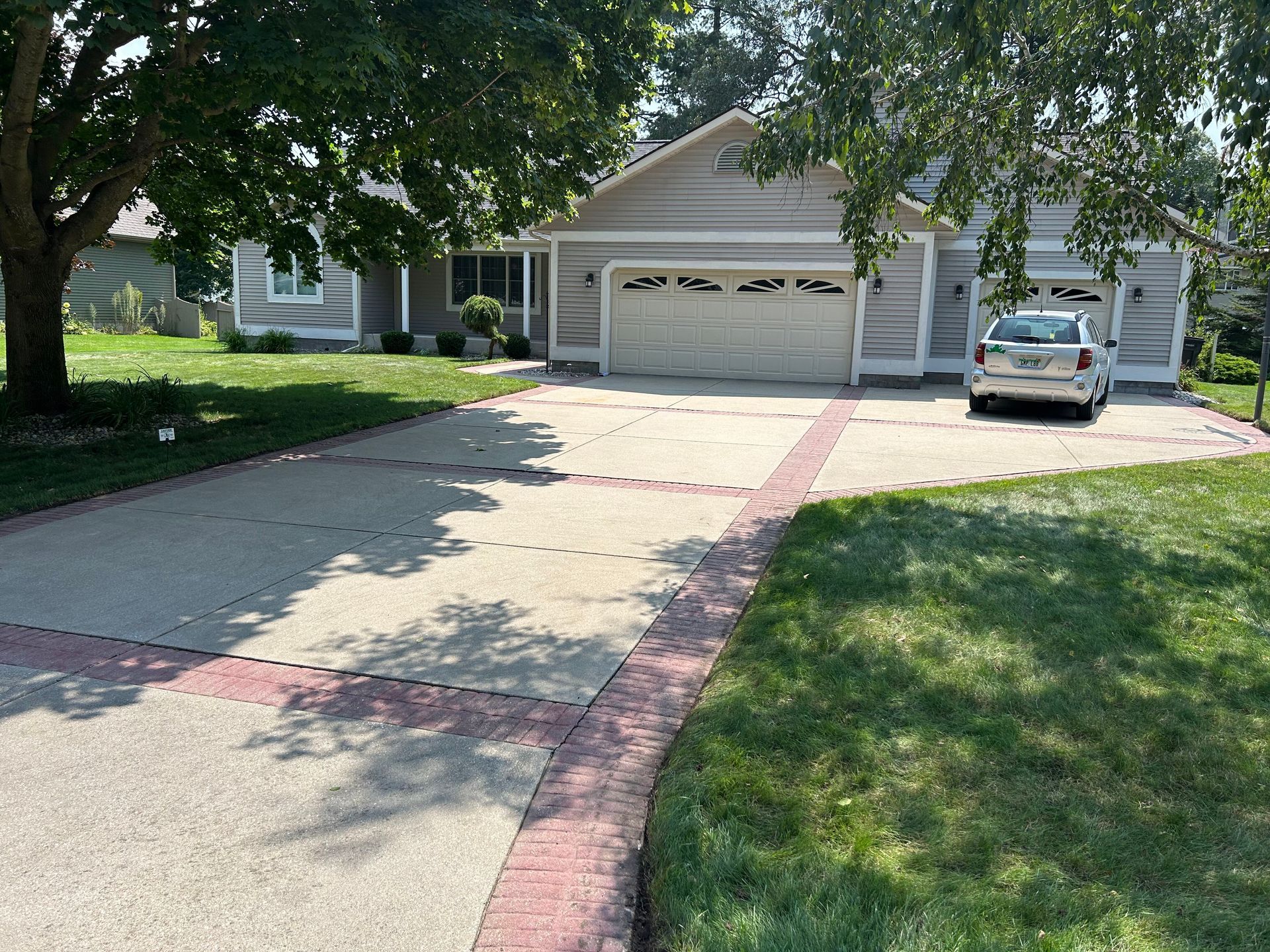 A car is parked in a driveway in front of a house.