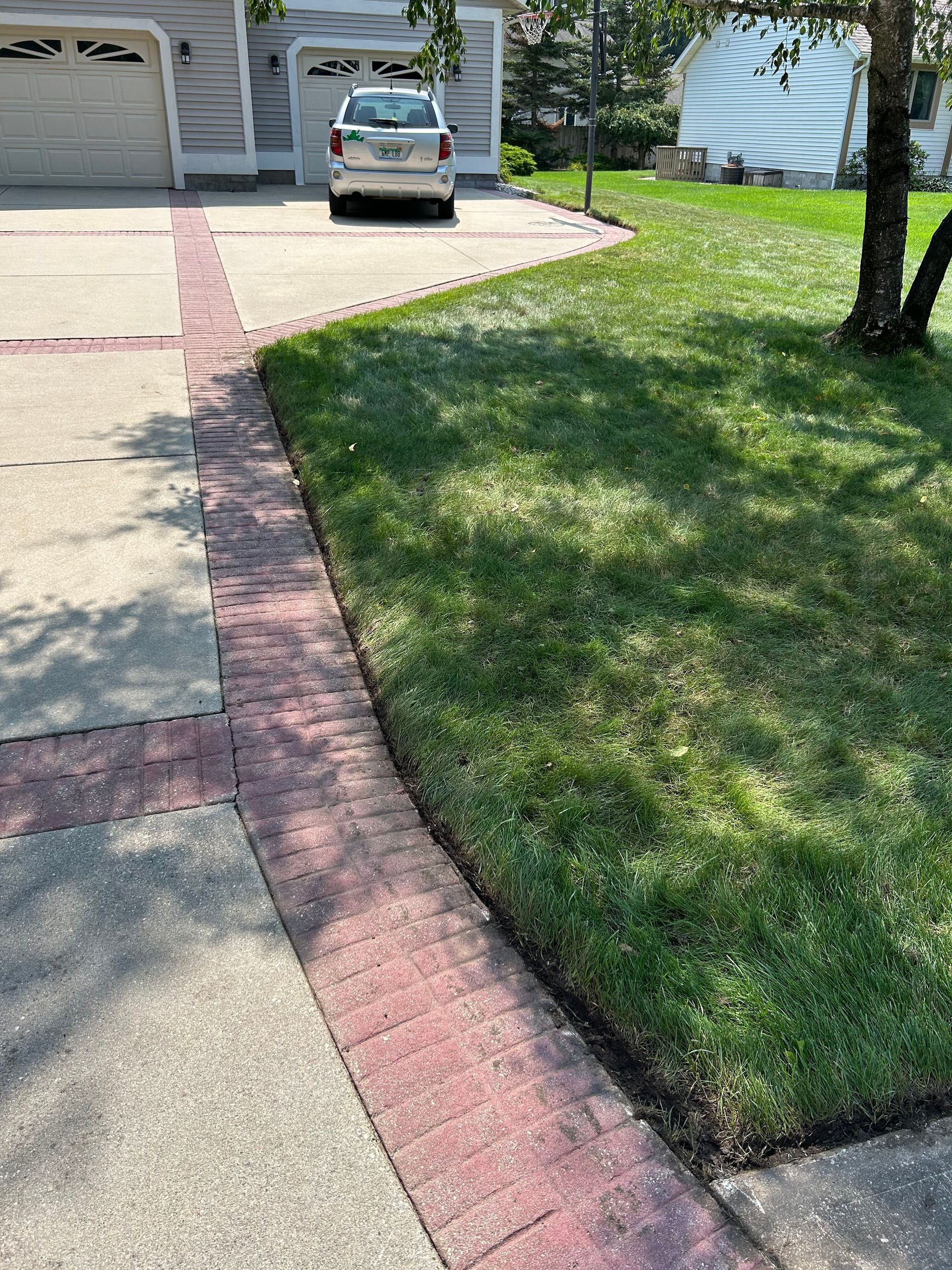 A car is parked in a driveway next to a lush green lawn.