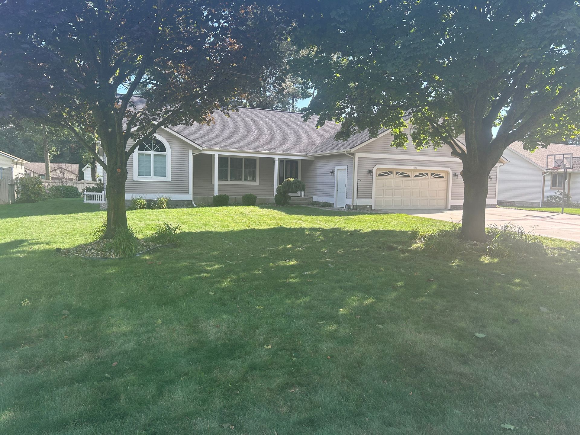 A house with a large lawn and trees in front of it