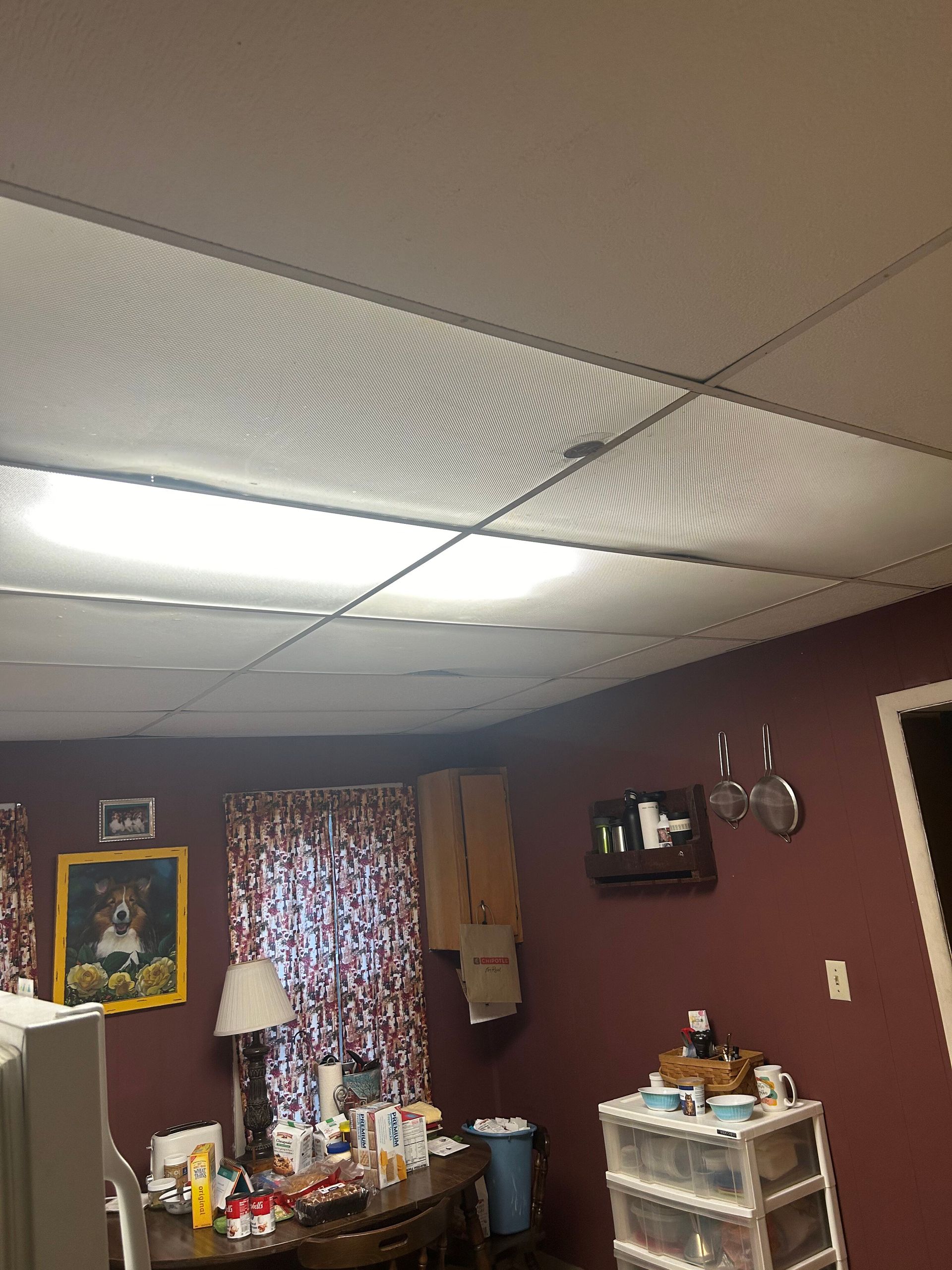 A living room with a table , chairs , and a ceiling light.